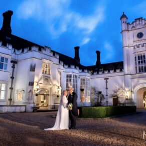 Floodlit pose of the newlyweds under dusky blue skies in the main courtyard of the fabulous Danesfield House Hotel in Buckinghamshire 