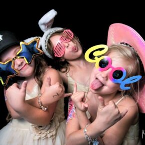 Three flower girls strike a crazy pose in the photo-booth during this evening wedding reception at Danesfield House Hotel   