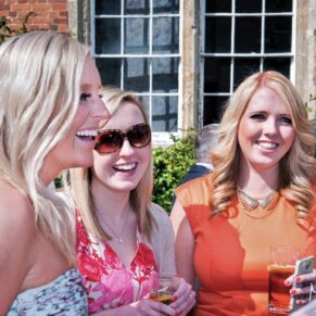 Candid capture taken during the outdoor drinks reception of three ladies giggling 