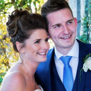 The bride captured with her brother under the portico with gorgeous lighting behind at her Dorton House wedding 