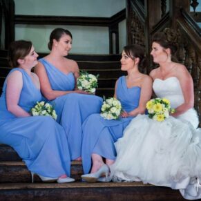 The bride sits on the staircase for an informal pose with her bridesmaids at her Dorton House wedding 