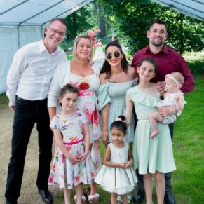 Relaxed family group pose inside the marquee at his summer marriage celebration
