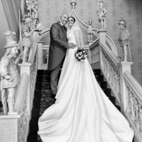 The newlyweds captured in a formal pose on the grand staircase during their wedding day celebrations at Hartwell House 