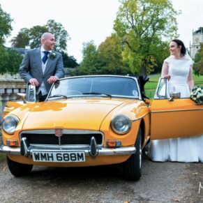 The newlyweds beside their vintage car on the bridge at Hartwell House  