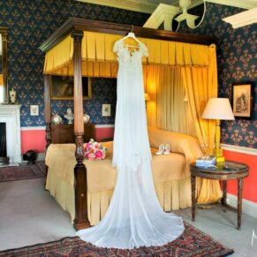 The bride's gown hanging from the four poster in the bridal suite at Hartwell House Hotel in Buckinghamshire 