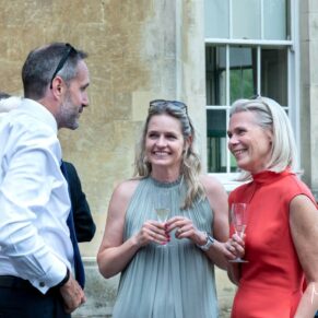 Reportage image capture of three smiling guests captured during the wedding drinks reception on the terrace at Hartwell House 