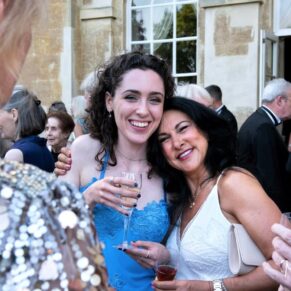 Relaxed image capture of two ladies having a hug during the wedding drinks reception on the garden terrace at Hartwell House 