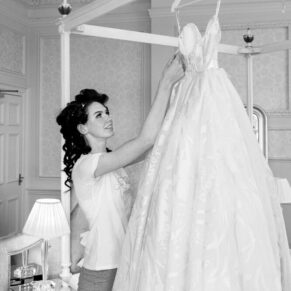 The bride makes some final adjustments to her gown in the bridal suite for this black and white capture at her Hedsor House wedding  