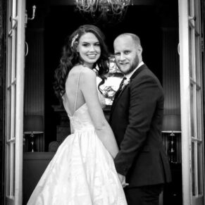 The newlyweds pose for my camera with a chandelier seen behind through the doorway at their Hedsor House wedding