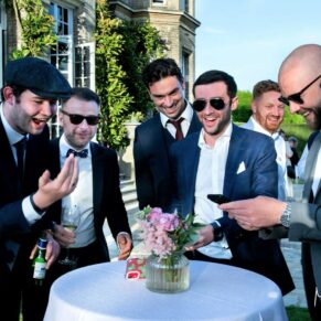 Some lively friends watch a big game of footie on their phone at this Hedsor House wedding 