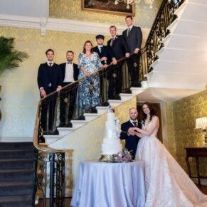 The family join the newlyweds for the wedding cake cutting on the staircase at Hedsor House 