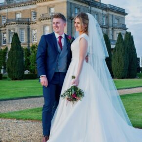 The bride and groom pose for a photo in the grounds during golden hour