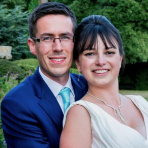 The newlyweds in a close-up pose in the gardens of their summer reception venue 