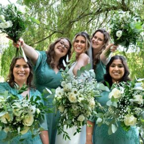 The bride larking around with her bridesmaids in the beautiful lush green gardens