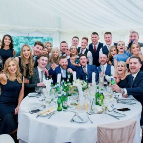 Large group of lively friends captured at their table in the marquee during the meal  