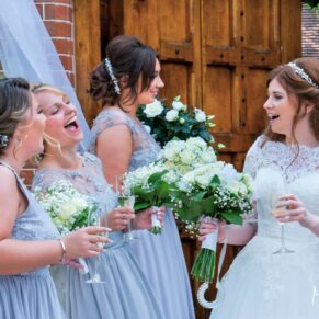 The bride giggling with her bridesmaids at the main entrance doorway at The Dairy 