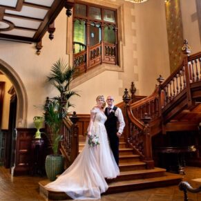 The newlyweds pose for the camera on the grand staircase at their Pendley Manor Hotel wedding 