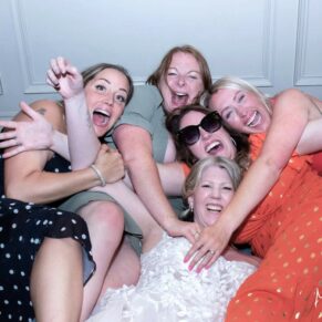The bride larking around with her girlfriends in the bar at her Pendley Manor Hotel wedding 
