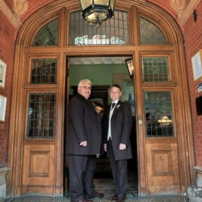 The groom and best man in the grand main entrance doorway at Pendley Manor Hotel 