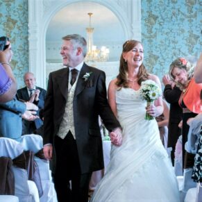 The newlyweds exit the indoor ceremony with big smiles at their at Pendley Manor Hotel wedding 