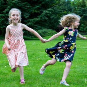 Two young guests darting around the gardens during the drinks reception at this Pendley Manor Hotel wedding