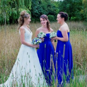 Runnymede Hotel Wedding Photography - the bride with her bridesmaids chatting in the grass meadow