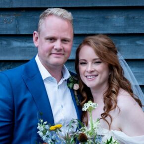 The Swan at Streatley Hotel wedding photography of the newlyweds posing for the camera against a rustic wooden backdrop 