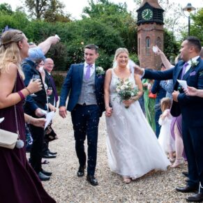 The bride and groom face a barrage of confetti from their guests as they are cheered through the aisle 