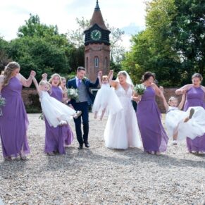 The bridal party walking together in front of the venue's clock tower  