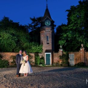The Tudor Barn floodlit at dusk with the newlyweds positioned in the foreground for a dramatic capture
