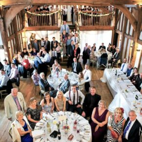 All of the wedding guests inside the barn as seen from the balcony at the Tudor Barn in Burnham 