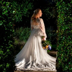 The bride lit up through the archway at night in The Olde Bell in Hurley's main gardens