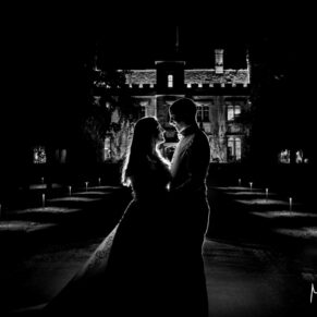 Dramatically li silhouette shot of the bride and groom captured at night-time in front of Weston Manor Hotel