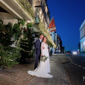 Photography of the newlyweds captured in front of the Christmassy Castle Hotel at dusk on their wedding day in Windsor 