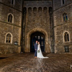 Photography of the newlyweds captured in front of Windsor Castle's dramatic main entrance after nightfall on their Castle Hotel wedding day