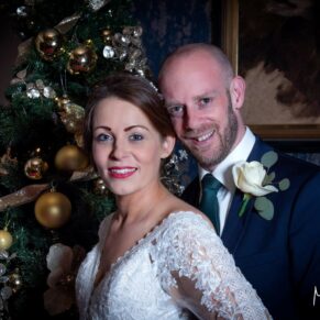 Photography of the happy newlyweds captured beside the Christmas tree at their Castle Hotel wedding in Windsor 
