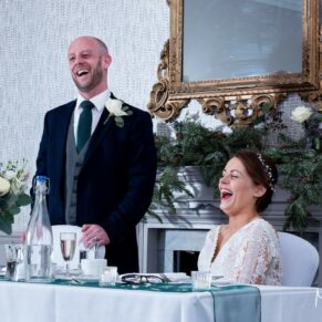 Photography of the bride giggling away during her husband's speech at their Castle Hotel wedding in Windsor 