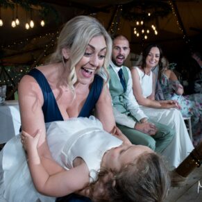 The bridesmaid and flower girl captured larking around during the evening reception withy the newlyweds watching on