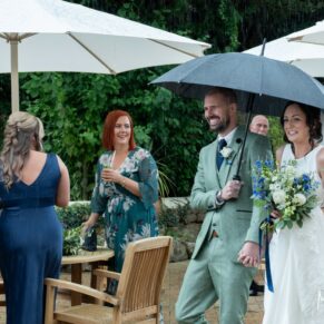 The newlyweds dash through a downpour to get back indoors during their rainy wedding day