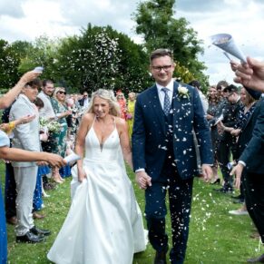 The smiling bride and groom dash through the colourful confetti aisle creating some great photography opportunities at their Latimer Estate wedding