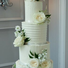 Photography of the stunning white floral arrangements on the yummy wedding cake located inside the Cavendish Suite on the Latimer Estate  