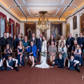 The newlyweds captured in a formal pose with all of their wedding guests in the grand historic setting of The Guildhall in Windsor