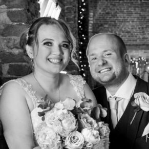 The bride and groom pose for a picture inside the barn