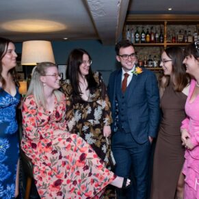 The groom enjoys some banter with his sisters in the bar area of the hotel
