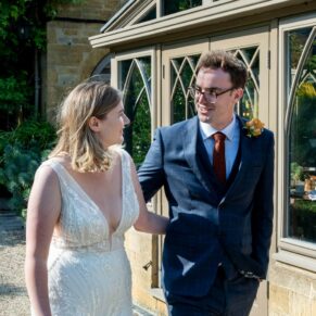 The smiling bride and groom take a stroll at the rear of the hotel