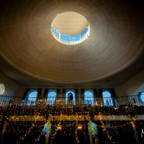 A dramatic wide angle shot of the wedding interiors at The Kings Chapel's in Old Amersham with the silhouetted newlyweds placed in a central window 