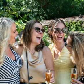 A candid wedding moment between friends filled with laughter in the gardens at The Kings Chapel Old Amersham 