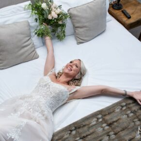 The bride collapses onto the bed at the end of a long day at her Kings Chapel Old Amersham wedding