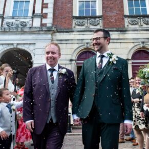 The smiling newlyweds navigate their way through the confetti aisle after their Windsor Guildhall wedding ceremony