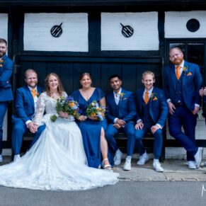 Photography of the newlyweds with their ushers casually sat on a bench prior to the wedding breakfast at their fabulous Buckinghamshire barn venue 